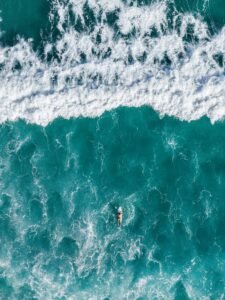 Stunning aerial shot of a lone surfer riding vibrant turquoise waves in Brazil's pristine waters.